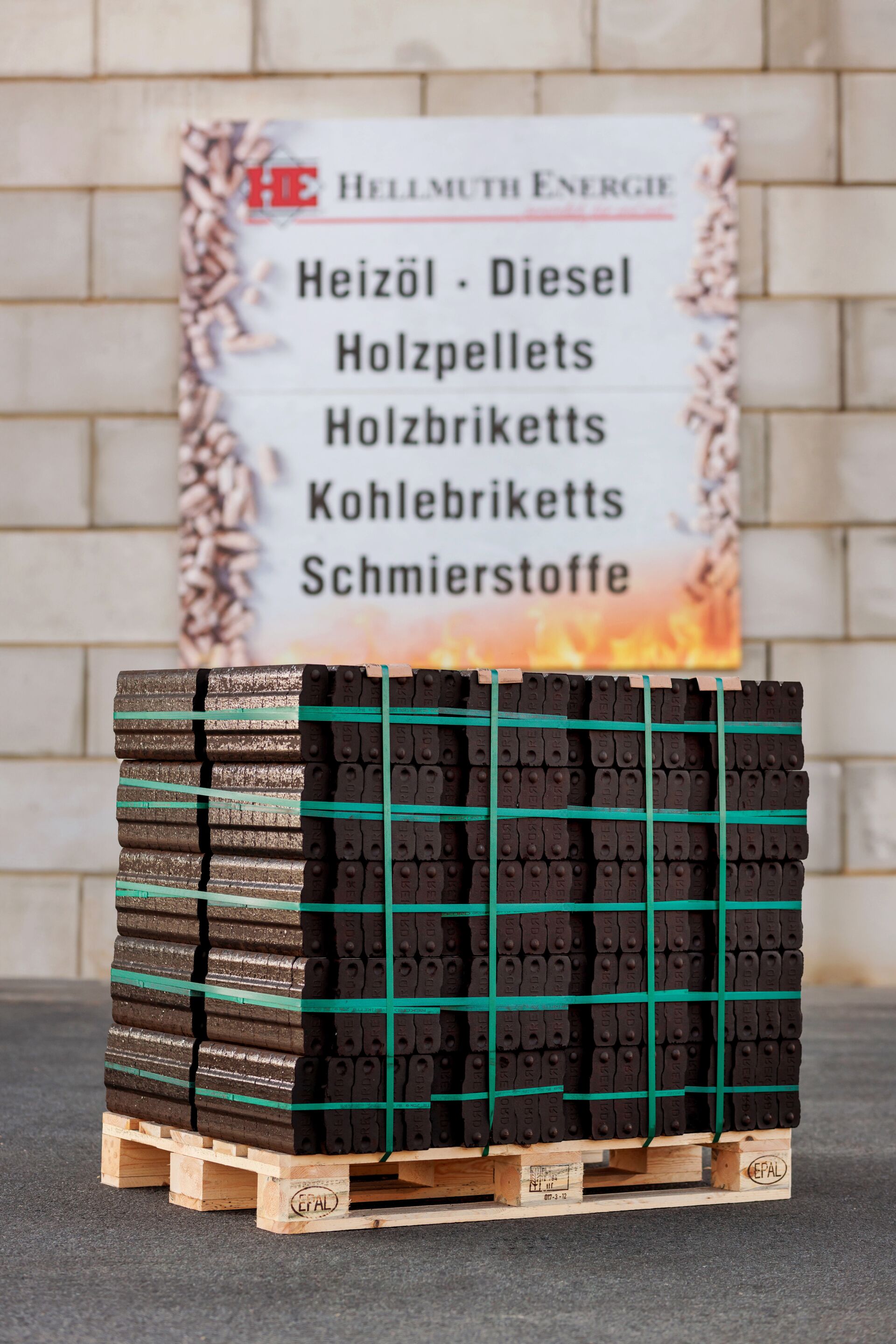 Kohlebriketts als Palettenware - Hellmuth Energie Werbung im Hintergrund